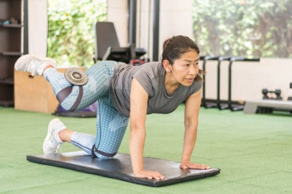 Latin woman training with dumbbell in gym